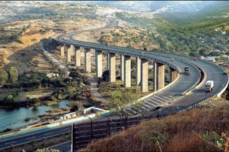 Aerial view of ongoing flyover and elevated corridor construction work in Pune with cranes, girders, and busy traffic below.