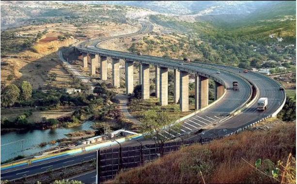 Aerial view of ongoing flyover and elevated corridor construction work in Pune with cranes, girders, and busy traffic below.