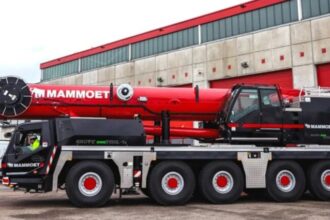 Manitowoc hybrid all-terrain crane with plug-in charging capability operating at construction site for low-emission lifting operations